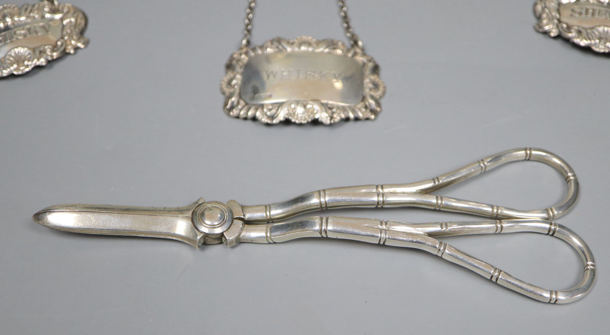 A collection of small silver to include a cased set of six coffee spoons and tongs, three wine labels and a pair of grape scissors